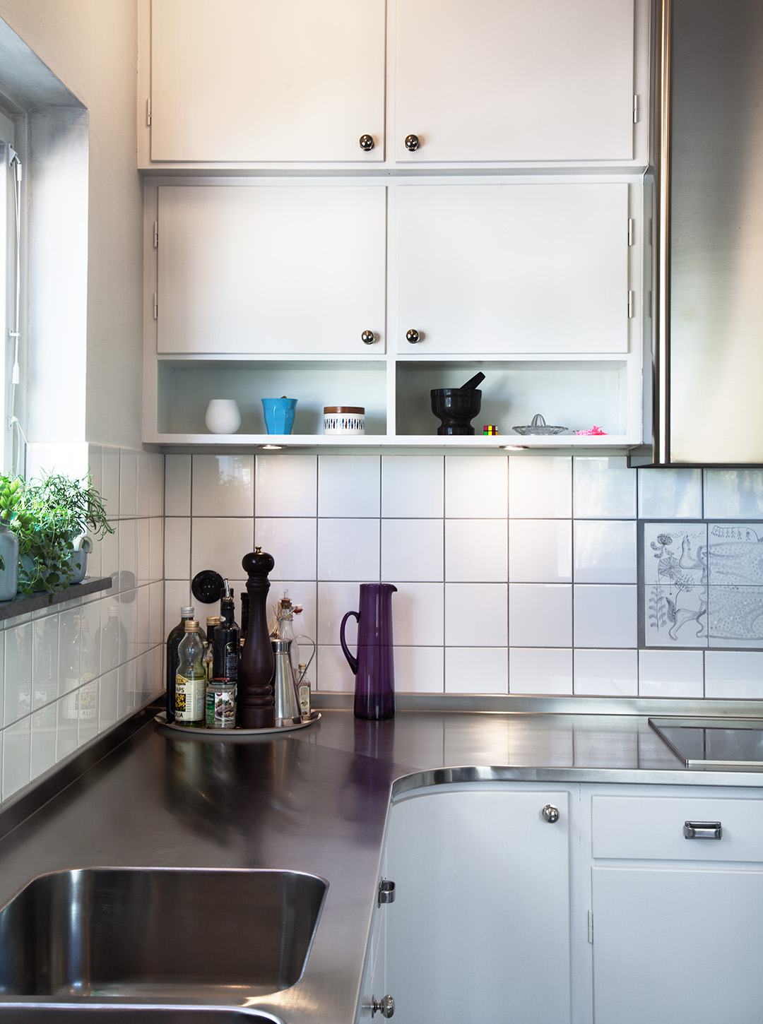 Måttbyggt kök i funkisstil med skarvlös bänkskiva som löper över inåtgående hörn. Även underskåpen följer samma form.